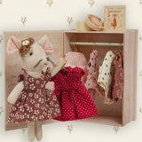 Toy mouse with dresses in a wooden wardrobe with floral wallpaper.